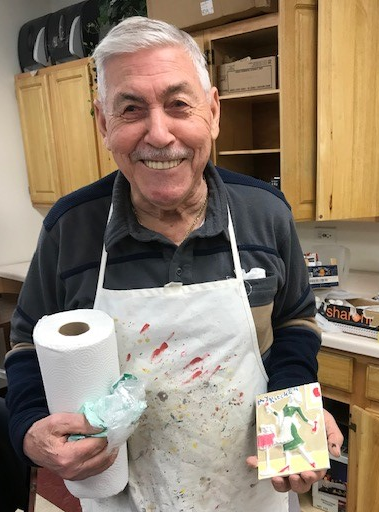 a senior resident smiling and showing his painting during the Safety and Creativity Classes