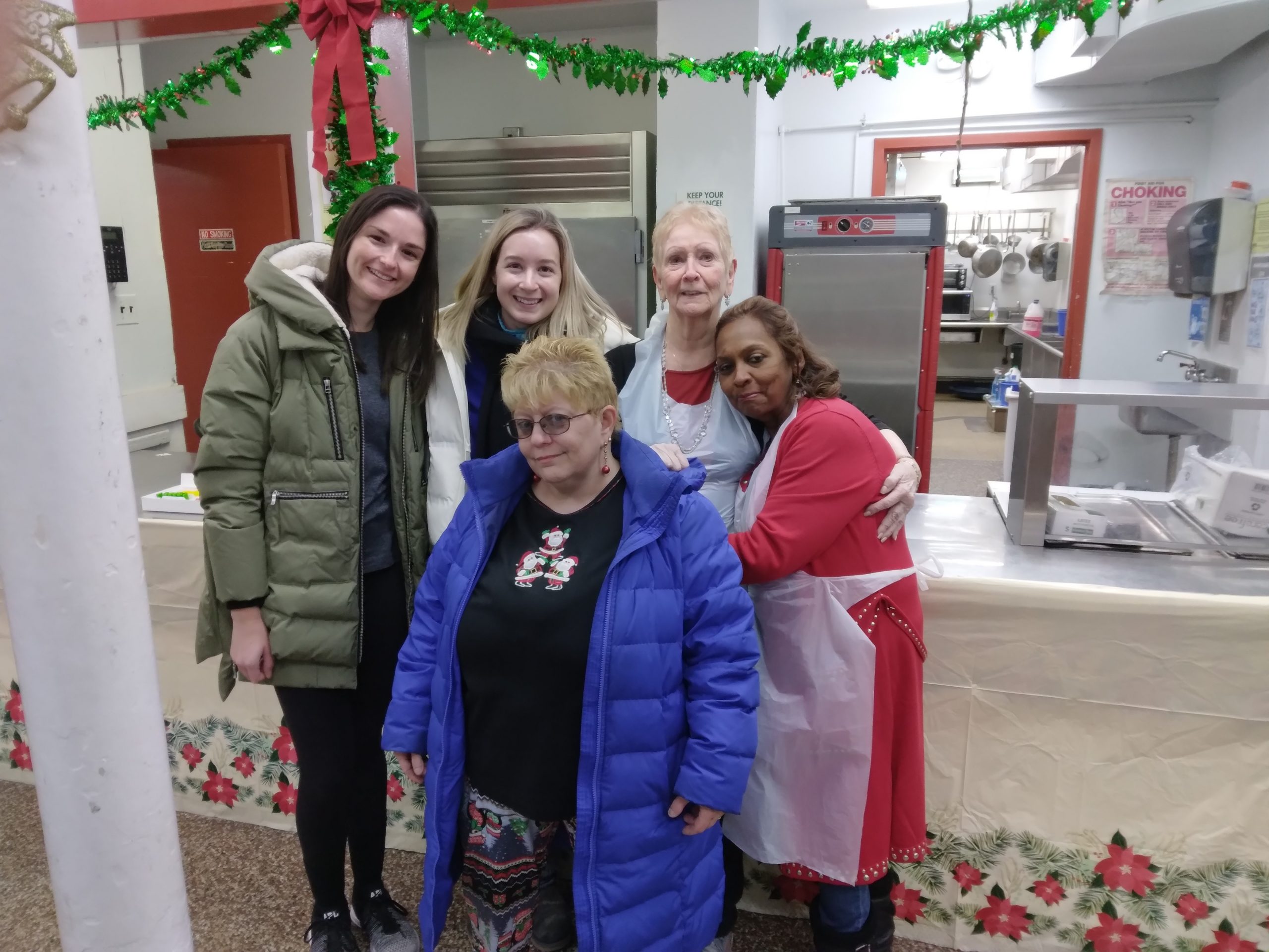 Intergenerational photo with young volunteers smiling and hugging seniors at the Ozone older adult center at Christmas