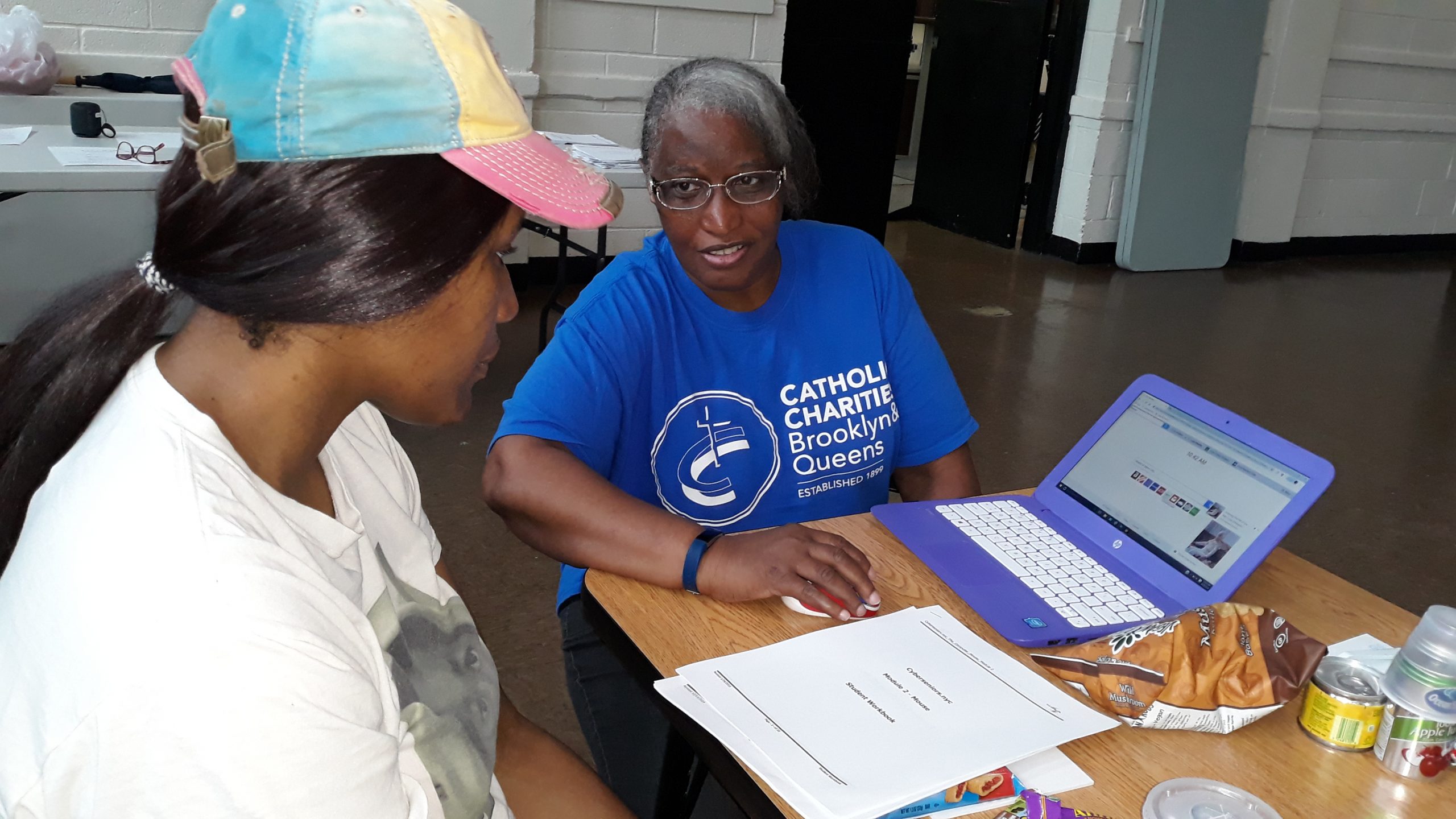 a catholic charities member is introducing to a guest computer skills during technical tuesday event