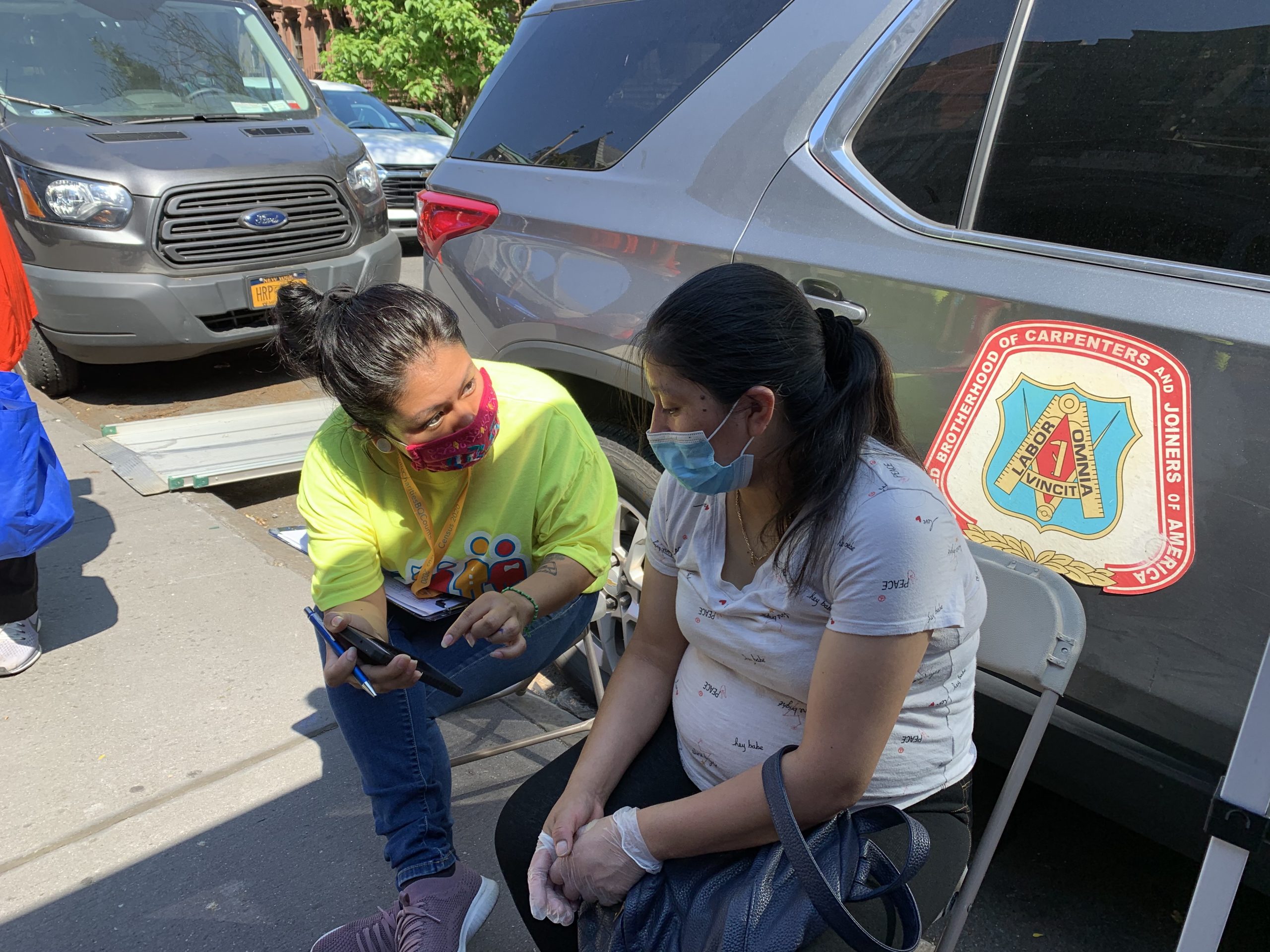 a census team member is showing a community member how to complete the #2020Census on her phone online