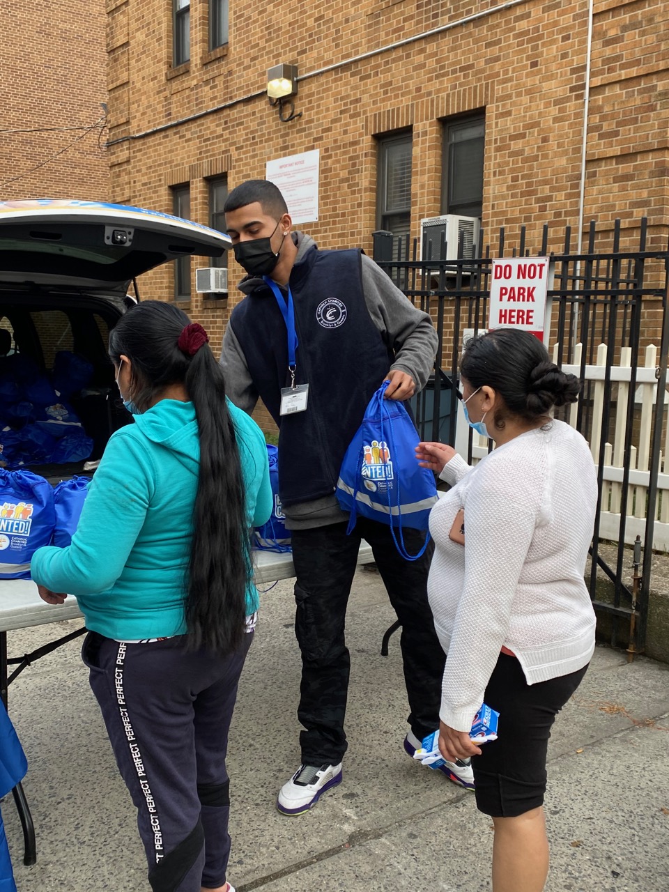 a staff from catholic charities brooklyn and queens distributing giftbags at a pop-up event