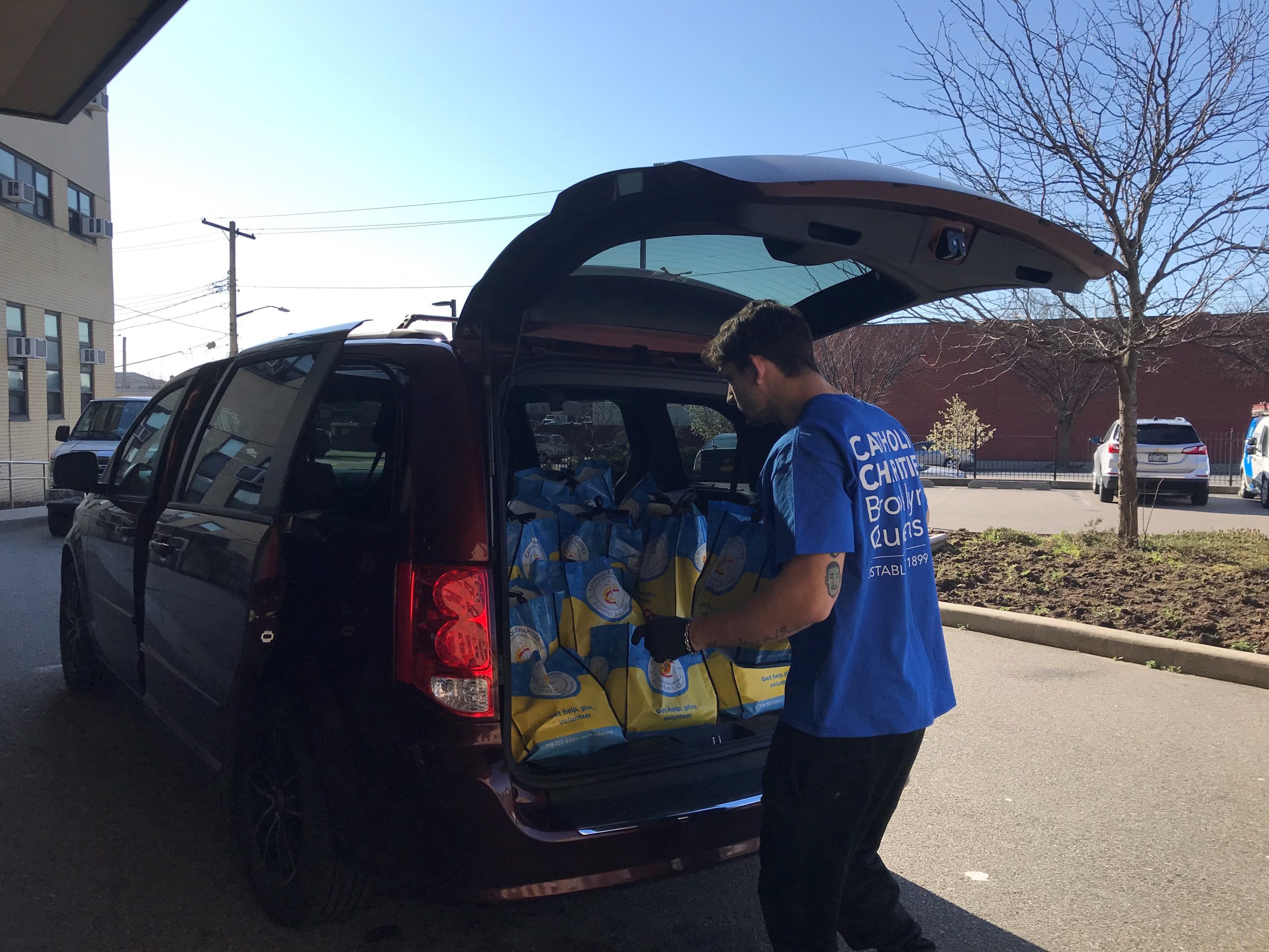 ccbq staff packing food bags in a car for senior residents as our work is continuing during coronavirus