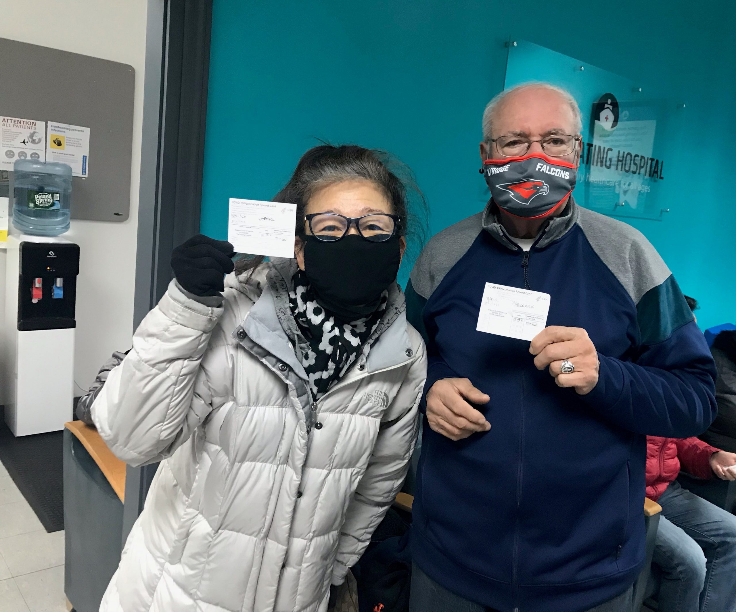2 older adults showing their COVID-19 vaccination card
