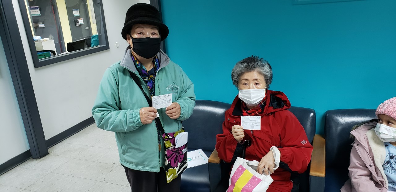 two senior residents showing their covid-19 vaccination card