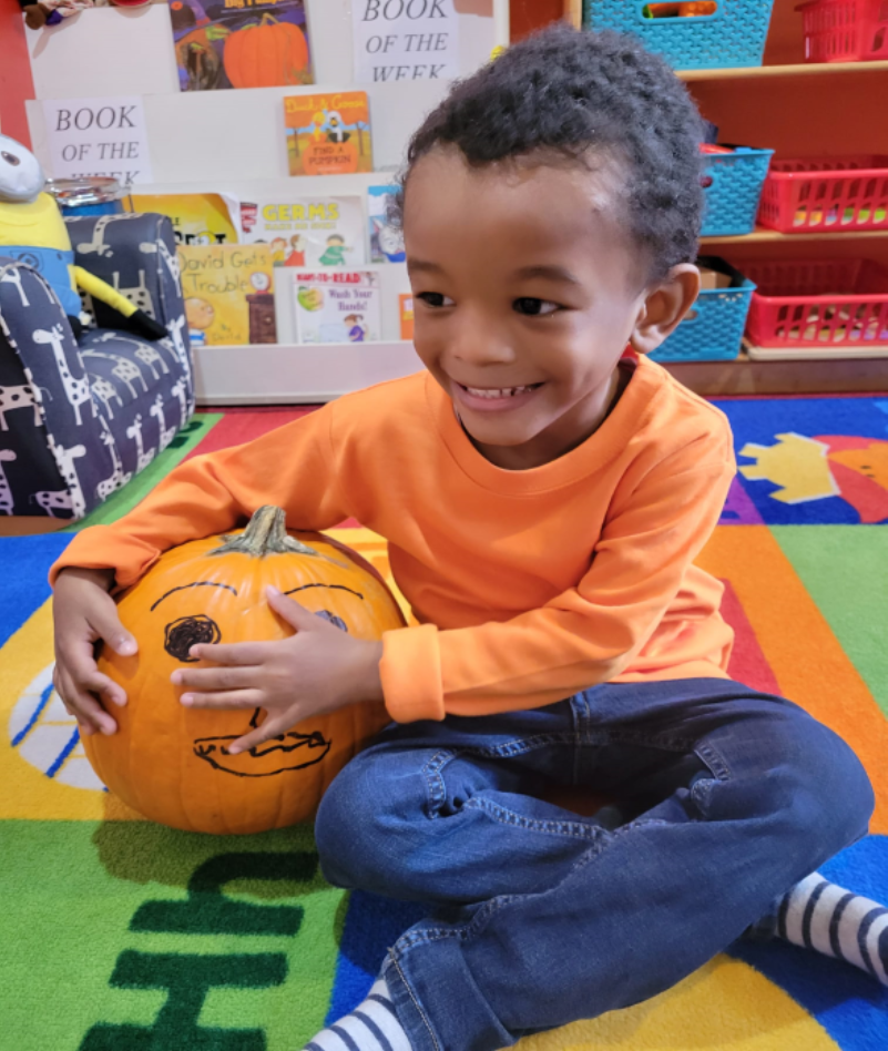 Student of Parkside Family Child Care with pumpkin from Pumpkin Patch