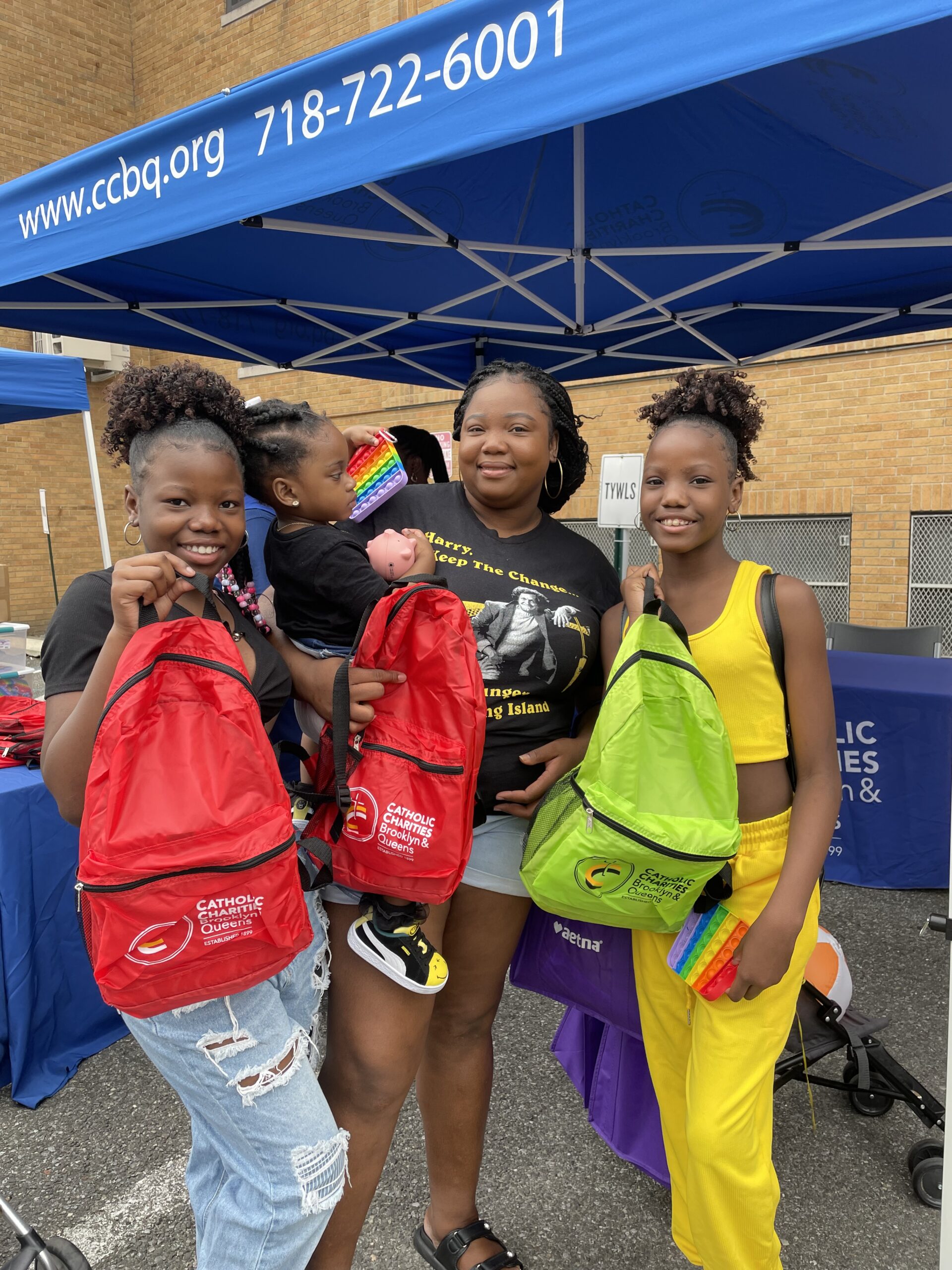 mother and her three kids showcasing their new bags during the 13th annual kids fun day back to school event