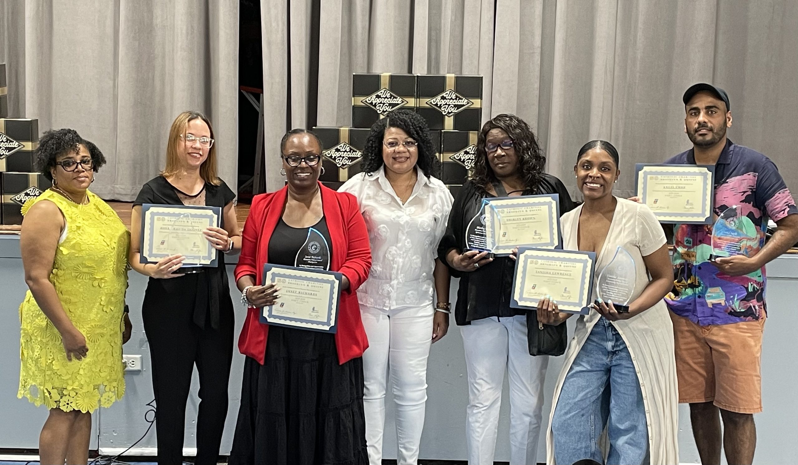 A group of smiling individuals, some holding certificates and awards.