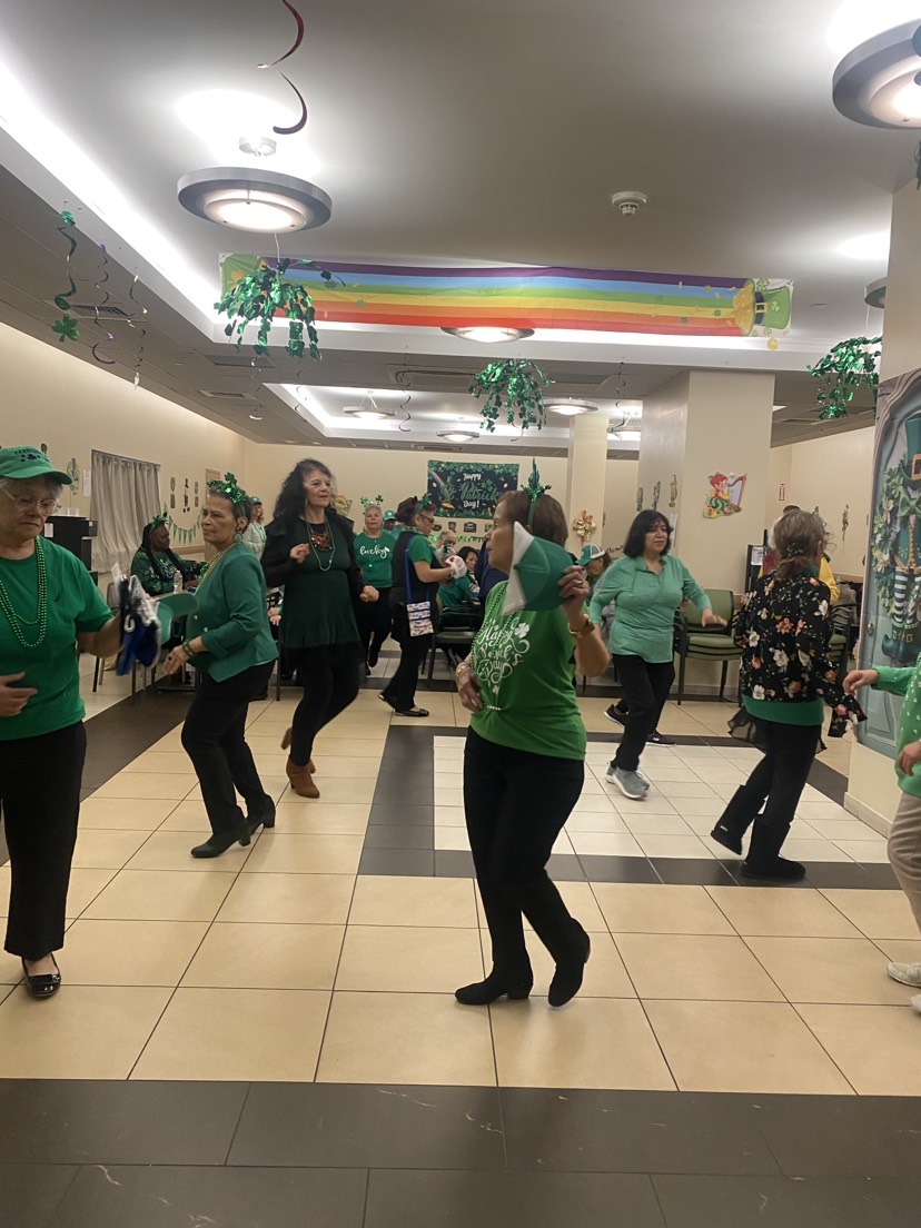group of seniors dressed in green and dancing on saint patrick's day at howard beach older adult center