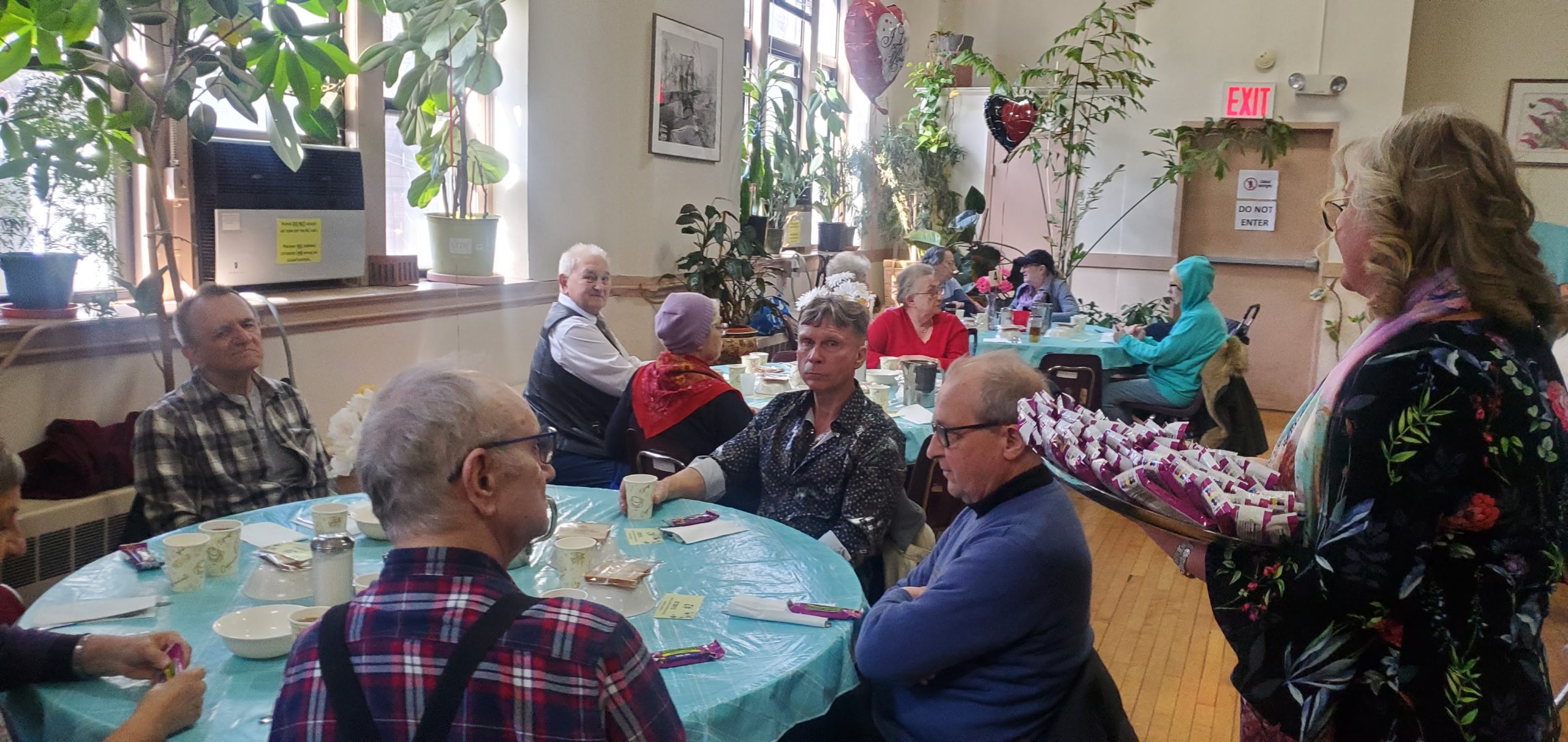 residents of pete mcguinness older adult center gathered at tables and celebrating international women's day