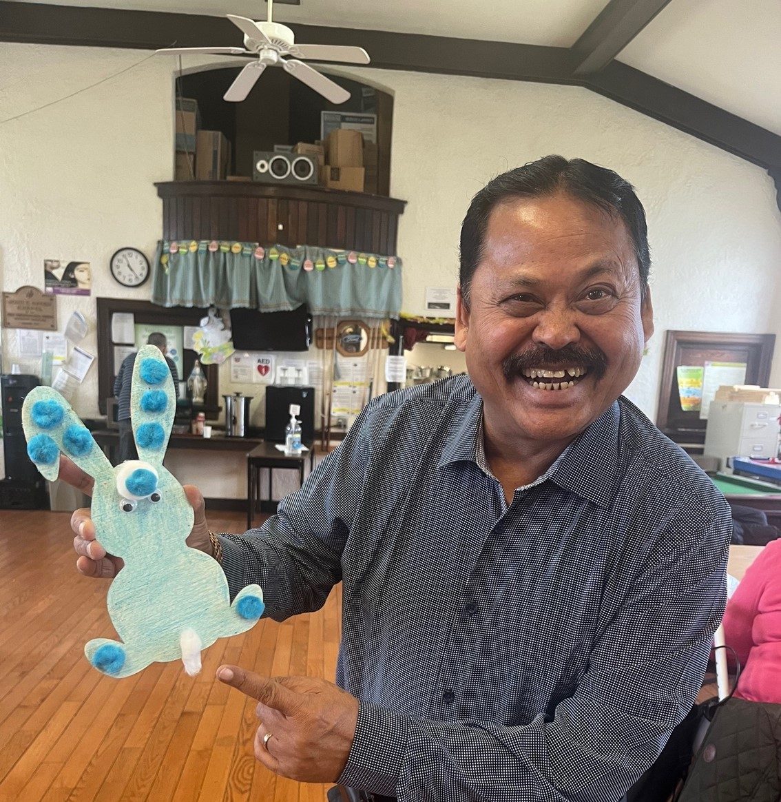 an older adult showing his crafted easter bunny at seaside older adult center