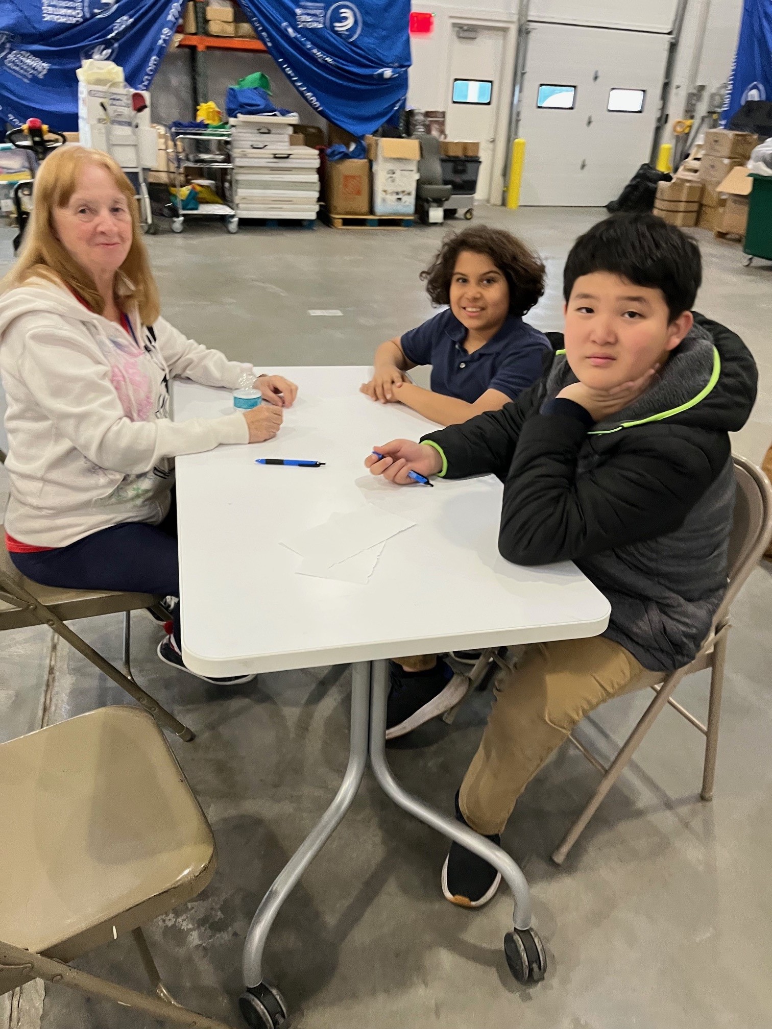 elementary school students and a community member smiling at a table during the gardening project