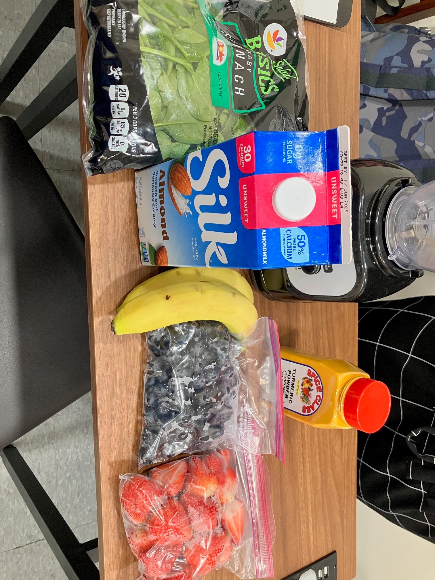 healthy ingredients presented at a table with a banana, blueberries, strawberries, turmerci powder and baby spinach