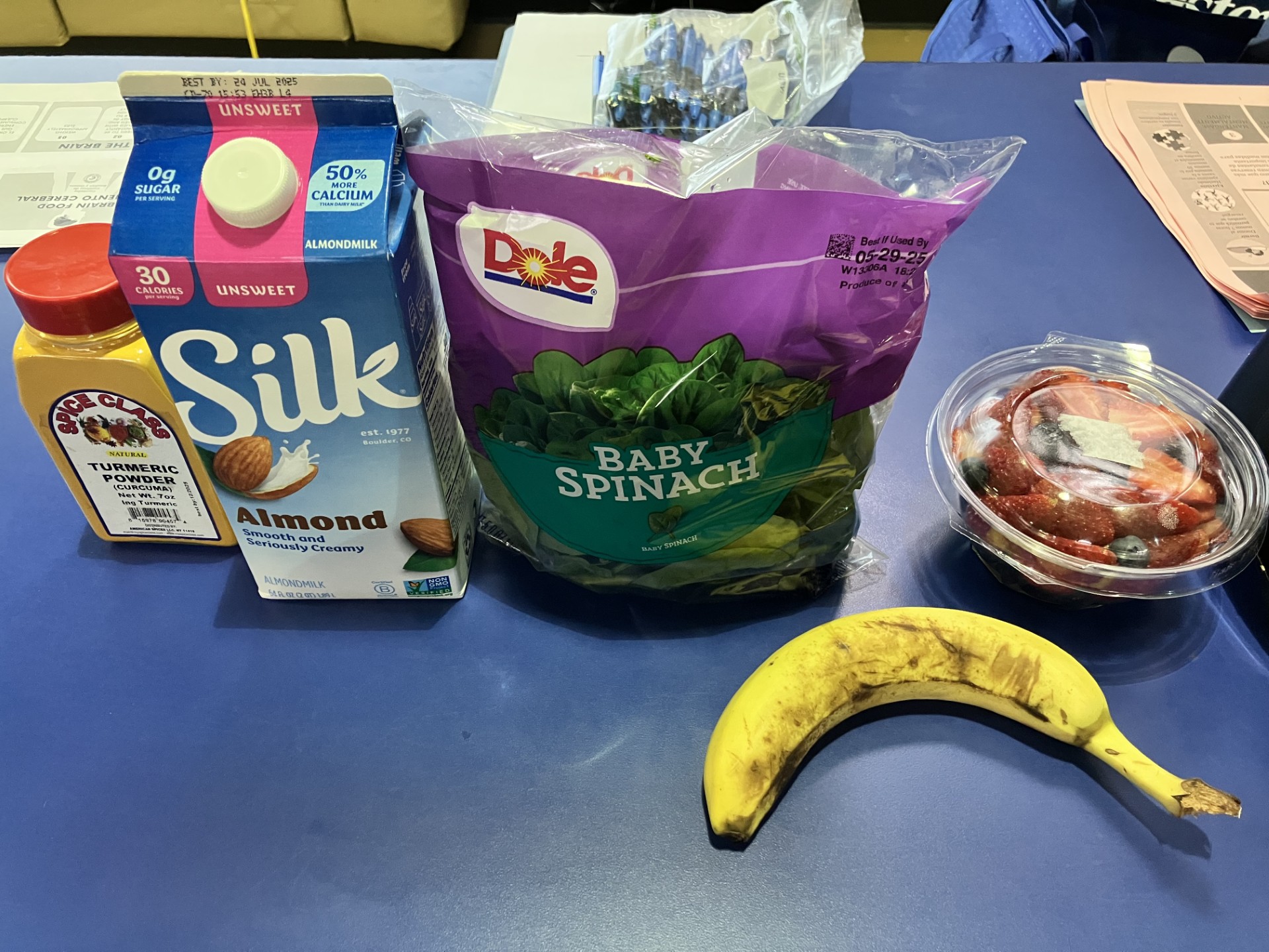 group of healthy ingredients such as a banana, a fruit bowl, a baby spinach bag, almond milk and turmeric powder during the brain food health workshop